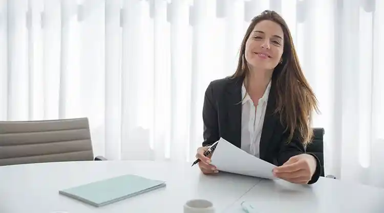 回访客户登录场景，一位职业女性微笑坐在办公桌前，象征安全访问账户与信任服务